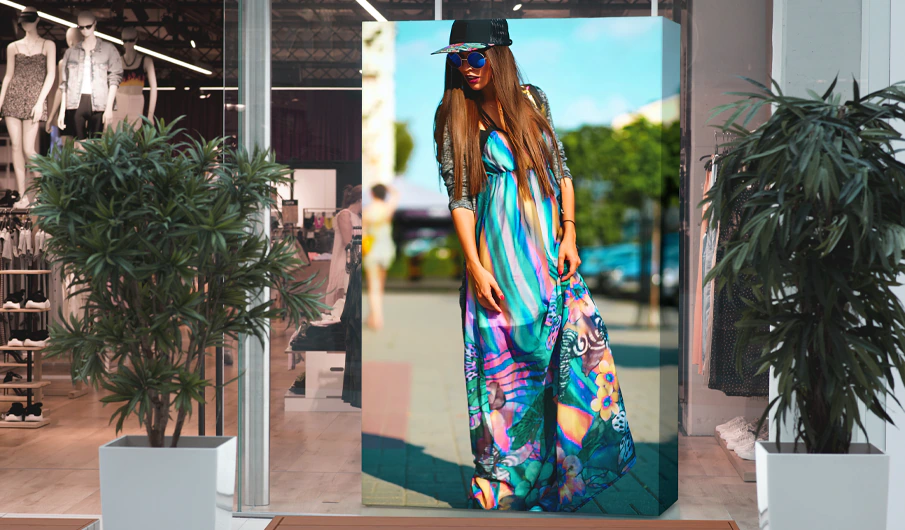 décoration de la vitrine d'une boutique de prêt-à-porter avec un caisson lumineux couvert d'une impression sur tissus tendu représentant une femme portant une robe d'été des lunettes de soleil et une casquette